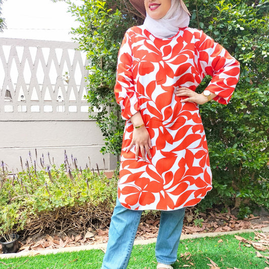 Person wearing a red and white floral dress with blue jeans outdoors