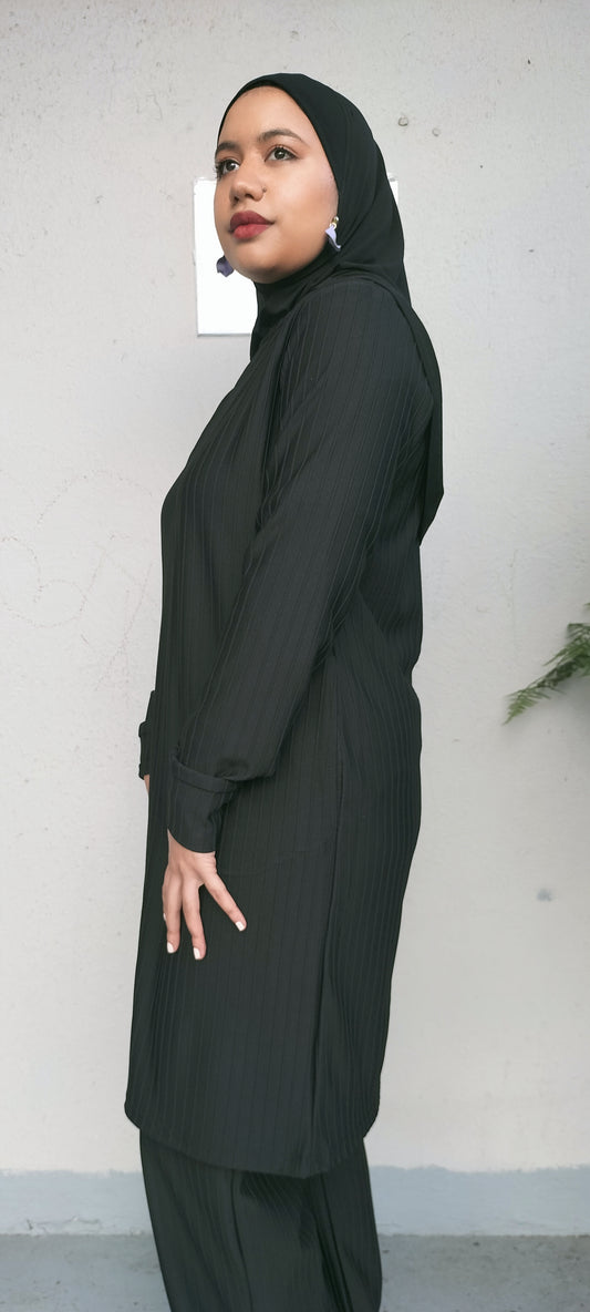 Woman wearing a black abaya against a plain background