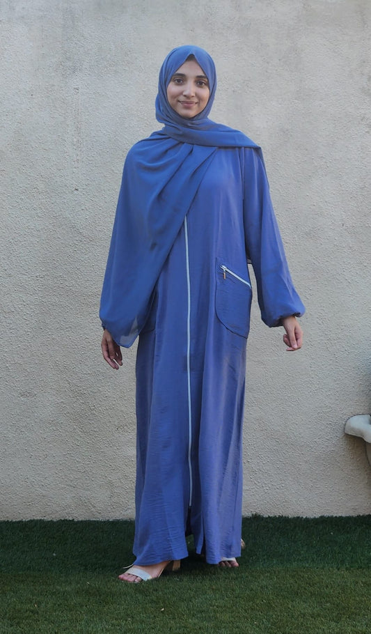 Person wearing a blue abaya against a plain background
